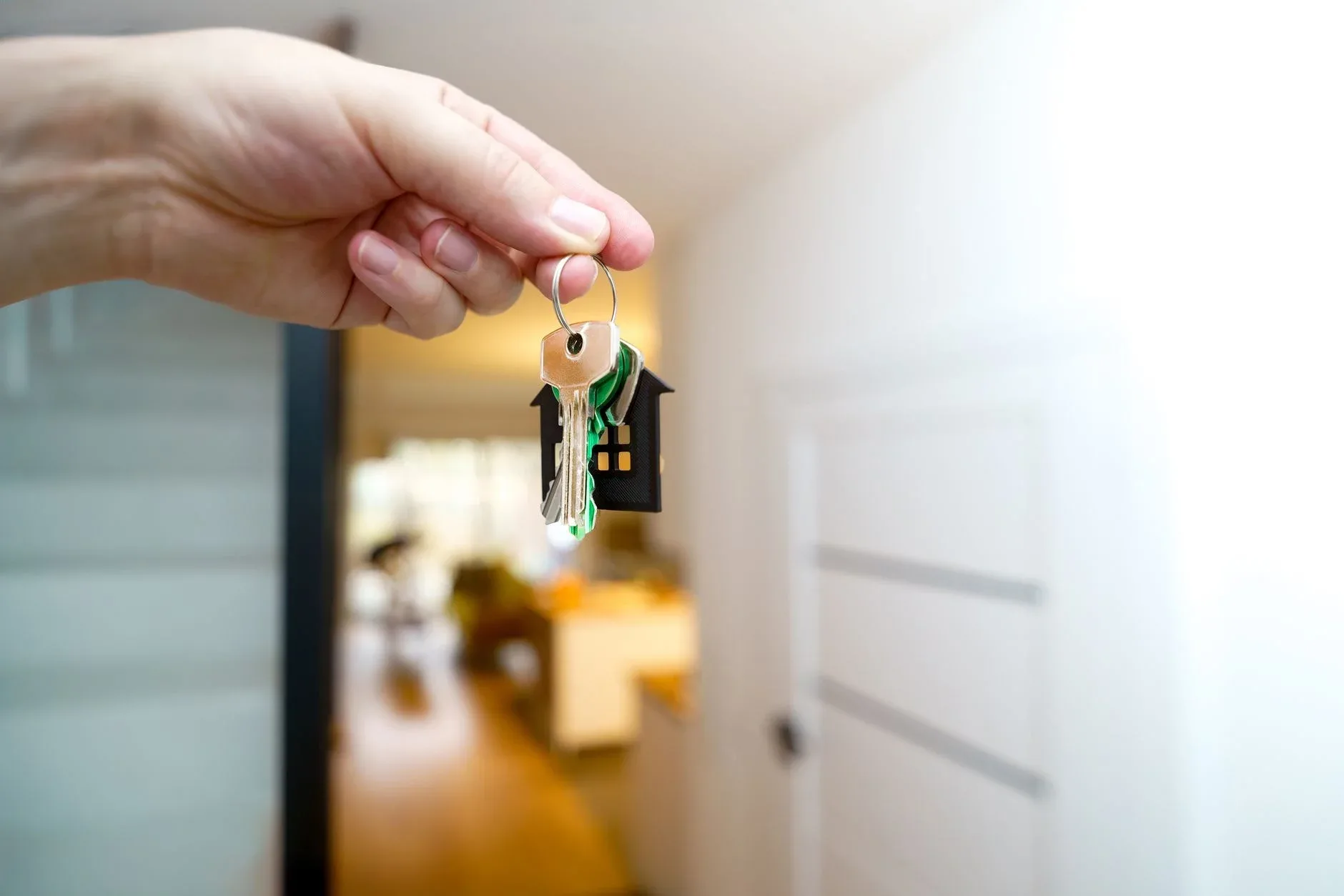 O mână care ține cheile unei noi locuințe într-un interior modern