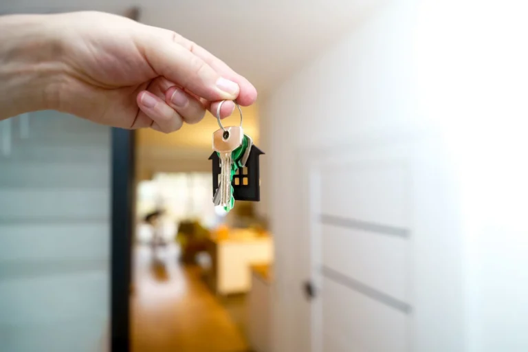 O mână care ține cheile unei noi locuințe într-un interior modern
